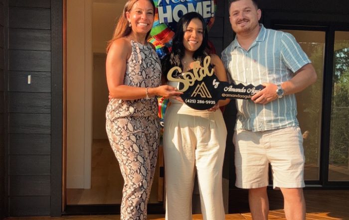 Amanda with clients holding a Sold sign on closing day